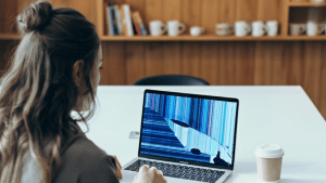 A woman looks at a MacBook with a distorted screen.