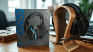 A Logitech G935 gaming headset in a box sits beside the actual headset on a wooden stand, placed on a wooden desk in a modern office setting