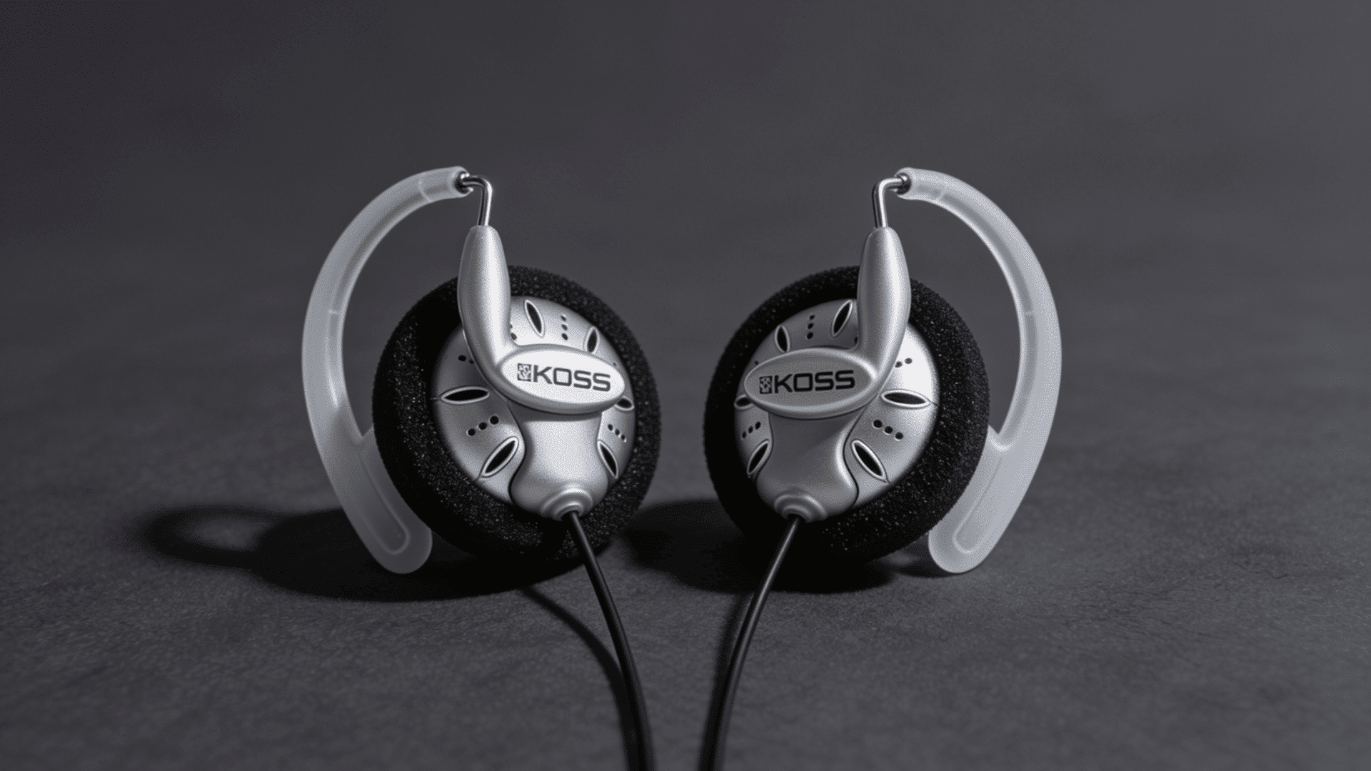 Koss KSC75 clip-on wired headphones in silver in a dark background.